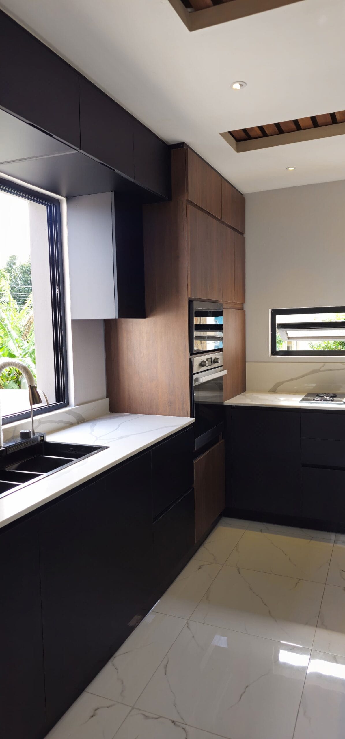 Modern black kitchen cabinets paired with a white quartz countertop with wooden accents and shelves